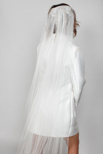 Close-up of the Samantha veil showing the large pearl and crystal bow at the crown, paired with a sleek Andrea Osei BRIDE white Renee blazer mini dress.