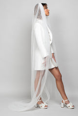Model wearing the Serendipity veil in striped tulle, chapel length, with soft vertical lines flowing over a tailored Andrea Osei BRIDE Renee blazer mini dress.